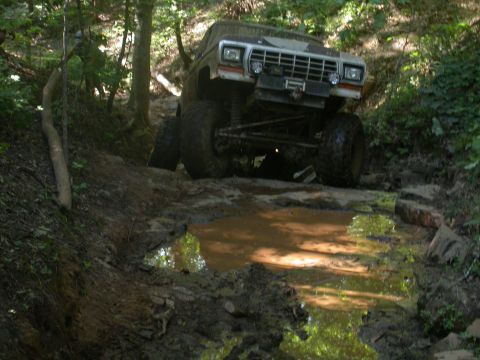 1990 Ford Bronco - This modified truck navigates a muddy trail through a wooded area.