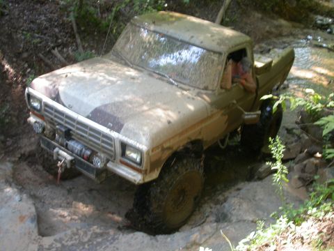 1990 Ford Bronco - This truck is covered in mud while driving through a challenging off-road course.