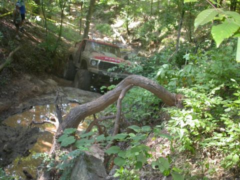 1990 Ford Bronco - A vintage pickup truck tackles a challenging off-road course, navigating mud and obstacles.