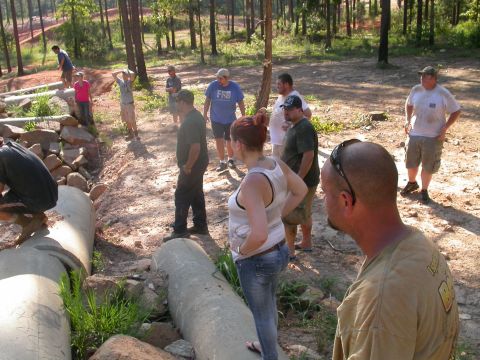 1990 Ford Bronco - A group of people observe a challenging obstacle course large concrete pipes in a wooded outdoor setting.