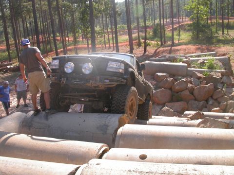 1990 Ford Bronco - This SUV is navigating a challenging off-road obstacle course made of concrete pipes and rocks.
