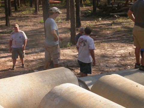 1990 Ford Bronco - People gather in a wooded area with large concrete pipes, with a website watermark visible at the bottom.