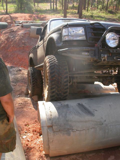 1990 Ford Bronco - This modified truck is navigating a challenging off-road course with large concrete pipes as obstacles.