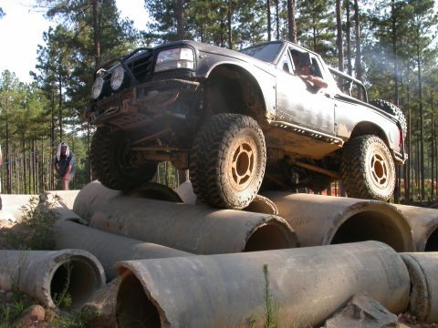 1990 Ford Bronco - A modified black Ford F-Series truck navigates an obstacle course made of large concrete pipes.
