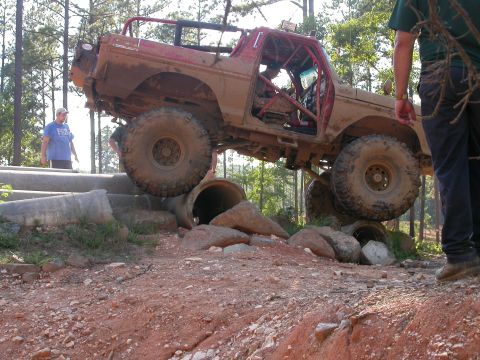 1990 Ford Bronco - Off-road vehicle with roll cage navigating rough terrain and obstacles. Likely a 1978 Ford Bronco.