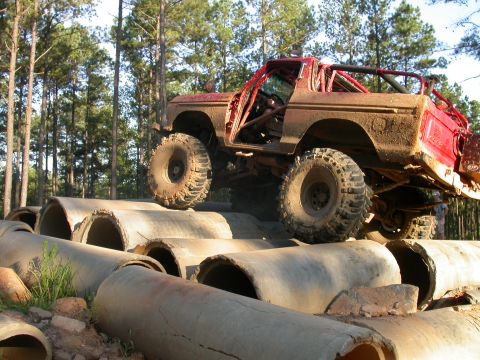 1990 Ford Bronco - This modified Ford Bronco is navigating a challenging obstacle course made of large concrete pipes.