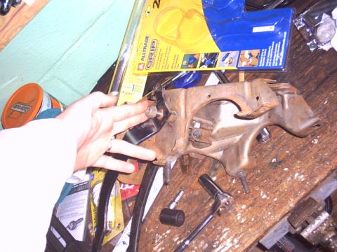 1991 Ford LTD Crown Victoria - A rusty car pedal assembly is shown with a hand and various tools scattered around it on a workbench.