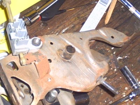 1991 Ford LTD Crown Victoria - Close-up of a rusted metal bracket, possibly a pedal assembly part, with an electrical connector and various tools scattered around.