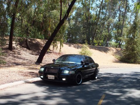 2003 Ford Crown Victoria - Close front view of a murdered-out sedan on dark wheels with a front plate