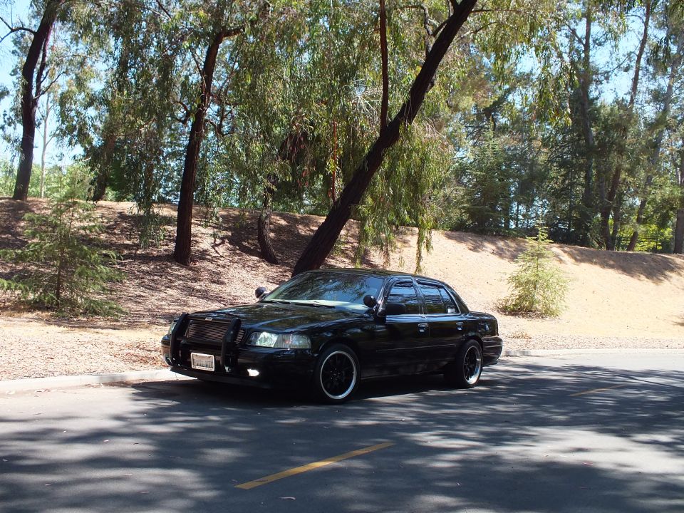 Black Mercury Grand Marquis sedan parked under trees on shaded road