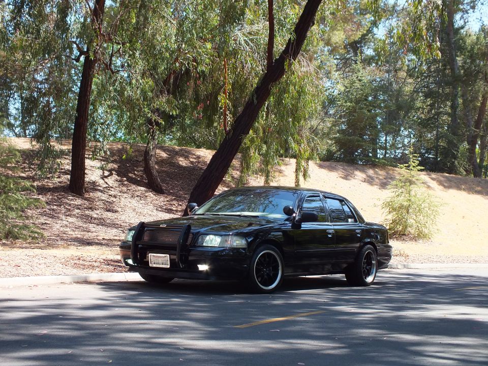 Black Mercury Grand Marquis with grille guard parked under trees