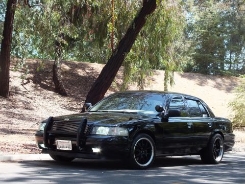 2003 Ford Crown Victoria - Front-left view of a glossy lowered black Mercury sedan on dark wheels.