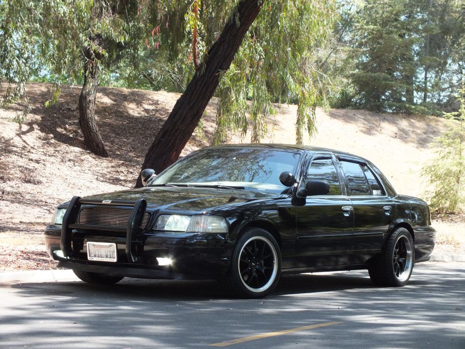 Black Mercury Grand Marquis with horizontal-bar grille parked under trees