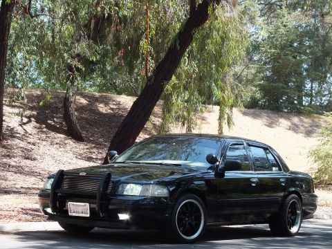 2003 Ford Crown Victoria - Front-left view of a glossy lowered black Mercury sedan on blacked-out wheels.