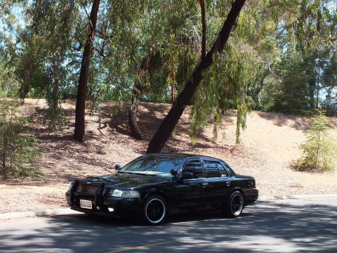 2003 Ford Crown Victoria - Lowered black Crown Victoria with grille guard photographed front-on by a dirt slope.