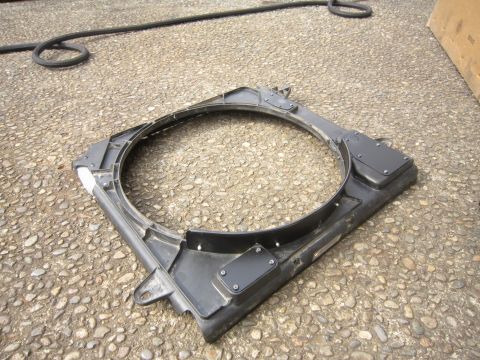 2008 Jeep Wrangler - A black plastic radiator fan shroud is shown lying on a gravel surface with a black hose coiled in the background.