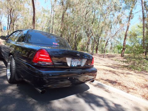 2003 Ford Crown Victoria - Rear three-quarter view of a blacked-out full-size sedan with twin exhaust tips.