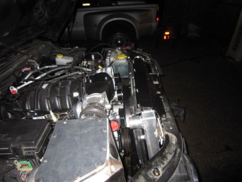 2008 Jeep Wrangler - Close-up view of a modified engine bay, a supercharger and new radiator, with another vehicle visible in the background.