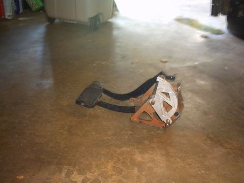1991 Ford LTD Crown Victoria - A detached assembly of car brake and accelerator pedals lies on a dirty concrete surface.