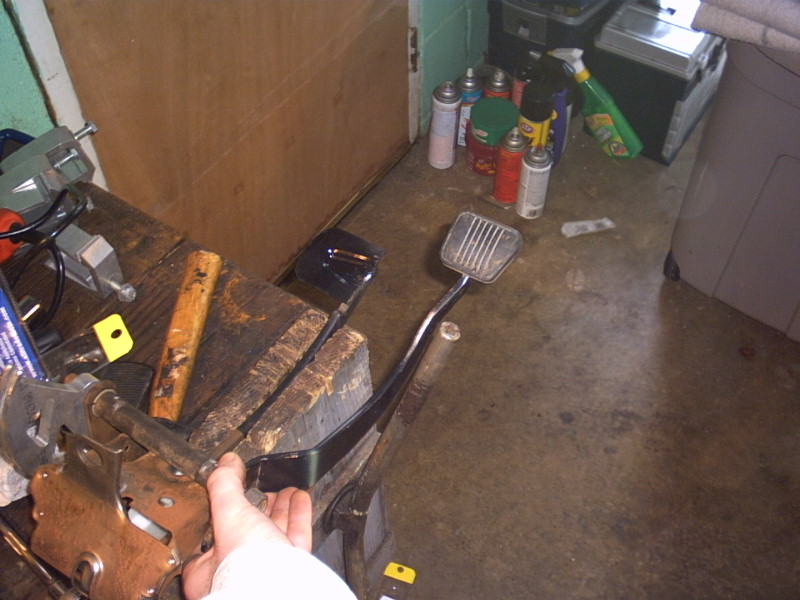 Car pedals on a workbench with tools and spray cans in the background
