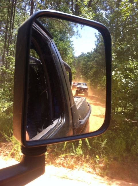 1979 Ford F-150 - A convoy of off-road vehicles travels down a dusty, tree-lined path.