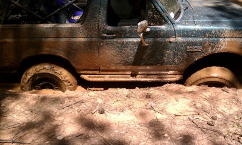 1979 Ford F-150 - This SUV is deeply stuck in mud, with only its tires and lower body visible.