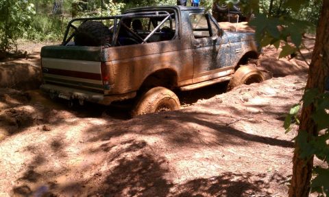 1979 Ford F-150 - Off-road truck stuck deep in mud during an outing. Another vehicle is visible in the background.