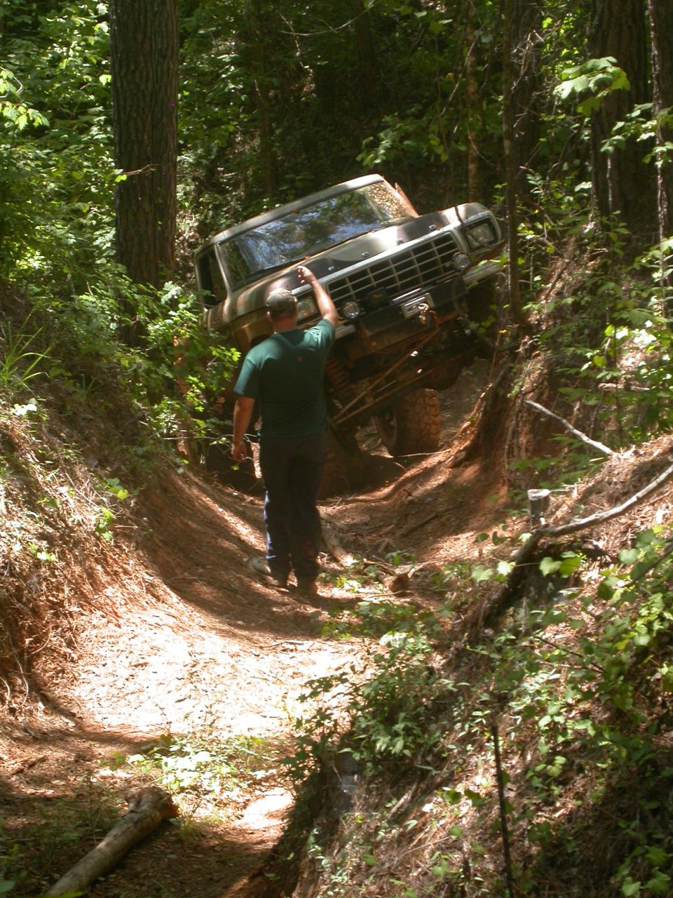 1979 Ford F-150 navigating a steep, wooded trail with a person guiding