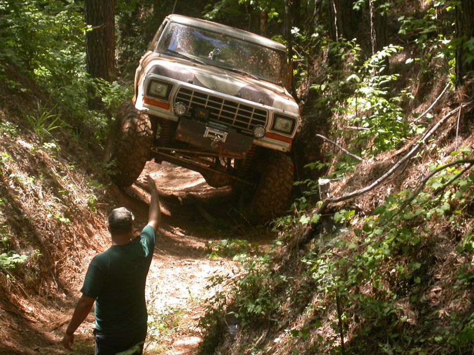 1979 Ford F-150 off-roading on a muddy trail with a person guiding