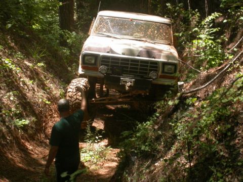 1979 Ford F-150 - A man watches as a 1979 Ford F-150 navigates a steep, wooded trail.