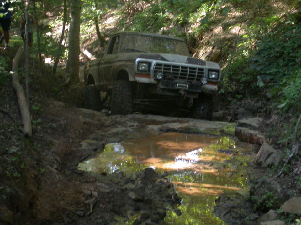1979 Ford F-150 driving through a muddy trail in the woods