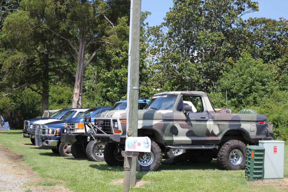 Several trucks and SUVs parked on grass, one in camouflage paint