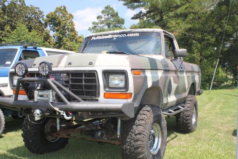 1994 Ford Bronco - A camouflaged Ford F-Series truck is parked on a grassy field, with another vehicle visible to its left.