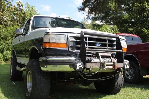 1994 Ford Bronco - This 1994 Ford Bronco features a prominent winch and brush guard, parked on a grassy lawn.