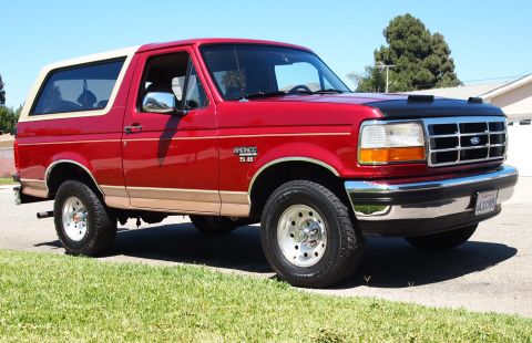 1994 Ford Bronco - Red 1994 Ford Bronco with tan two-tone trim and a white top is shown from the front three-quarter view.