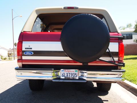 1994 Ford Bronco - Rear view of a red and tan 1994 Ford Bronco, a spare tire mounted on the tailgate and a California license plate.
