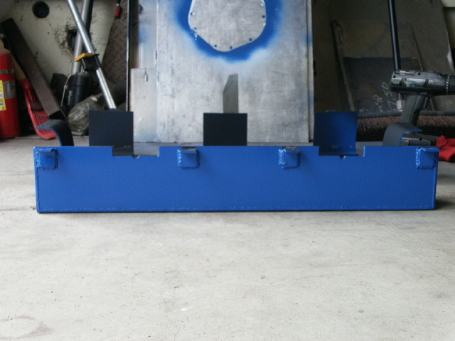Freshly painted blue steel bracket with tabs on concrete garage floor