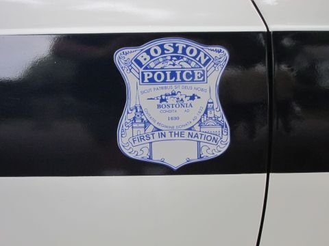 1991 Ford LTD Crown Victoria - Close-up of a Boston Police shield decal on a black-and-white car door, reading 'First in the Nation' and 'Bostonia 1630'.