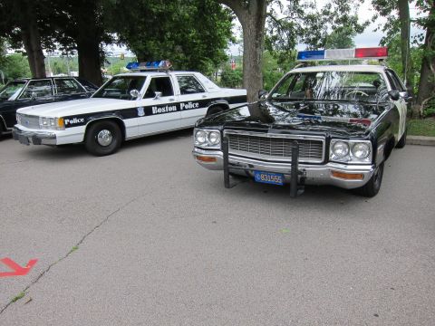 1991 Ford LTD Crown Victoria - black-and-white Boston Police Ford sedan parked beside a darker cruiser fitted with a push bumper and Massachusetts plate 831555.