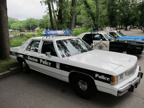 1991 Ford LTD Crown Victoria - black-and-white 'Boston Police' Ford sedan with blue roof lightbar parked near a pond, alongside other vintage police cars including a High…