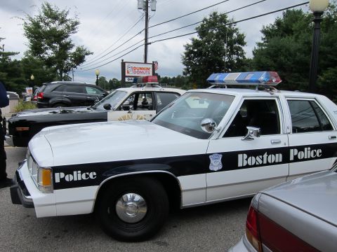 1991 Ford LTD Crown Victoria - black-and-white 'Boston Police' Ford cruiser with roof lightbar parked among other police cars at a Dunkin' Donuts parking lot.
