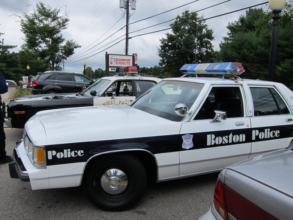 Black and white Boston Police Ford cruiser parked at a Dunkin Donuts lot