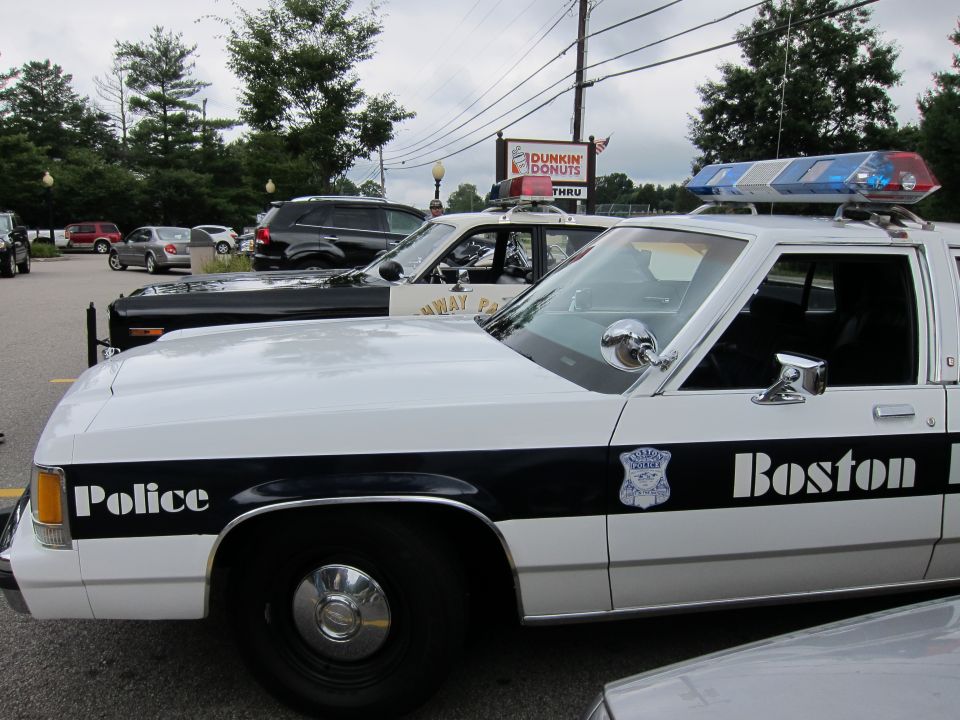 Black and white Boston Police Ford cruiser side view at a Dunkin Donuts lot