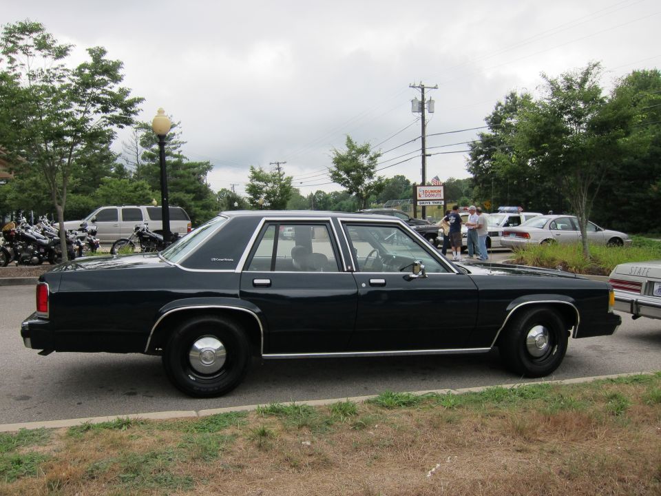 Side view of dark blue four-door Ford police sedan with black wheels