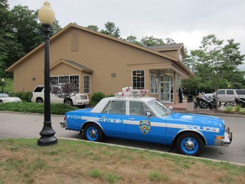 1991 Ford LTD Crown Victoria - blue NYPD Highway Patrol sedan marked HWY 3 with a roof light bar sits along a curb near a tan building.