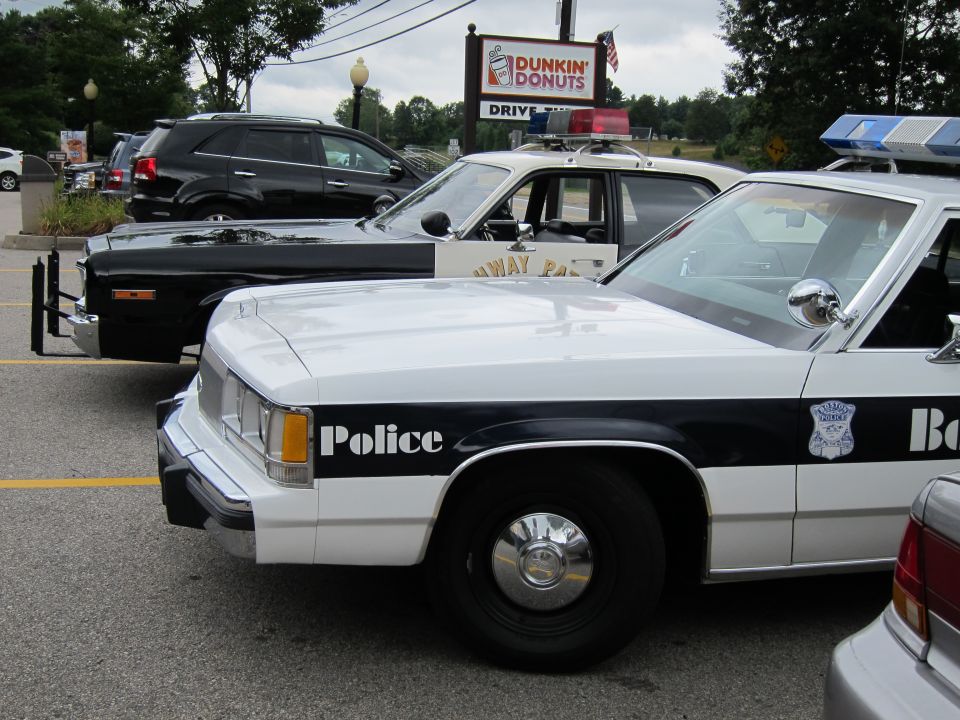 White-and-black police cruiser fronts parked beneath a Dunkin Donuts sign
