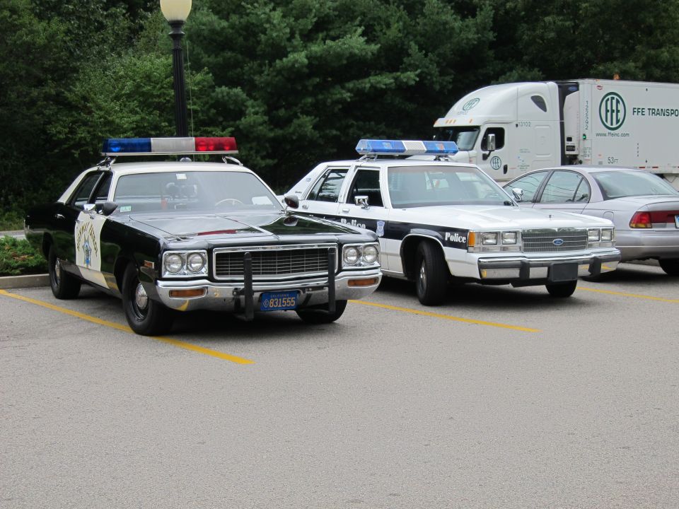 Black-and-white police sedan and white cruiser with FFE truck behind