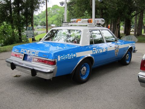 1991 Ford LTD Crown Victoria - Rear three-quarter view of a blue NYPD Highway Patrol sedan numbered 2840 with a roof light bar parked near trees.