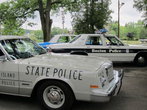 1991 Ford LTD Crown Victoria - Close angle of a silver State Police sedan hood with a white-and-black Boston Police car parked behind it under trees.