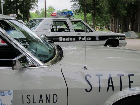 1991 Ford LTD Crown Victoria - Tight composition of a silver State Police sedan fender lettered ISLAND and STATE with a Boston Police car in the background.